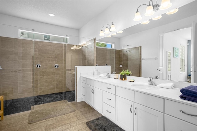 bathroom featuring wood-type flooring, a chandelier, vanity, and a tile shower