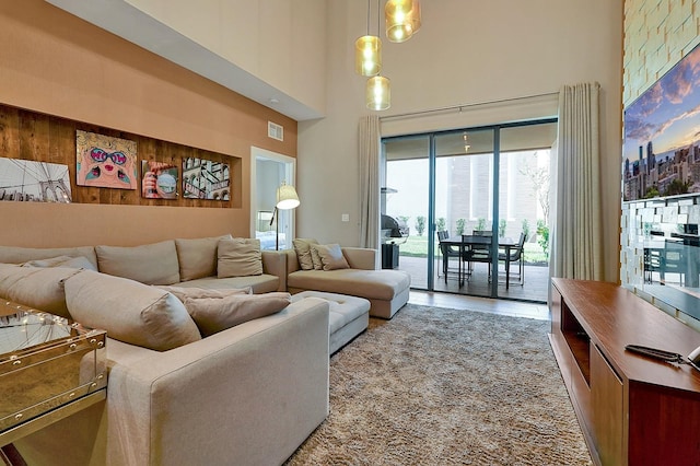 living room featuring wood walls, a chandelier, and a towering ceiling