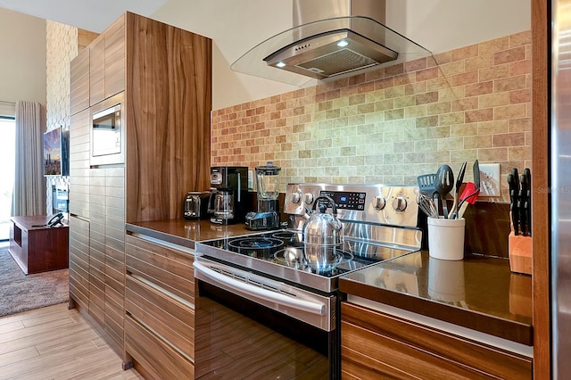 kitchen with tile walls, wall chimney exhaust hood, appliances with stainless steel finishes, and light carpet