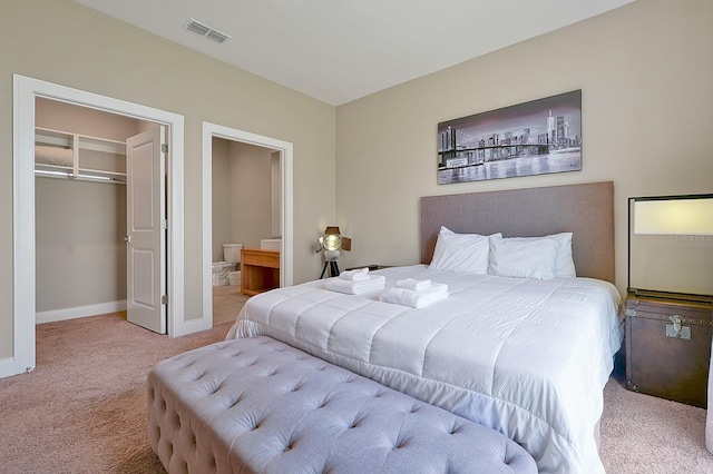 bedroom with light carpet, a walk in closet, a closet, and ensuite bathroom