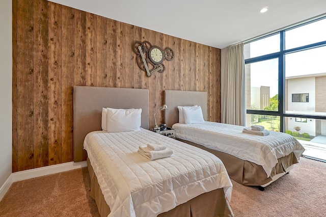 carpeted bedroom featuring wooden walls and a wall of windows