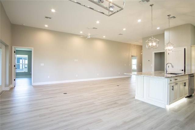 kitchen with a wealth of natural light, light stone countertops, light hardwood / wood-style floors, and ceiling fan with notable chandelier