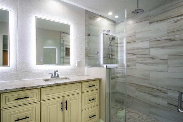 bathroom with tile walls, walk in shower, vanity, and backsplash