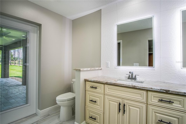 bathroom featuring tile walls, toilet, tile floors, tasteful backsplash, and vanity