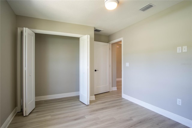 unfurnished bedroom with a closet and light wood-type flooring