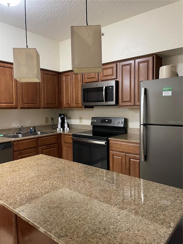 kitchen featuring dark stone counters, hanging light fixtures, stainless steel appliances, a textured ceiling, and a sink