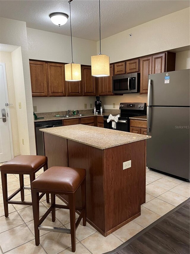 kitchen featuring a textured ceiling, stainless steel appliances, a kitchen island, and pendant lighting