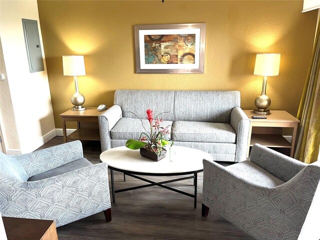 living area with a textured wall, baseboards, and wood finished floors