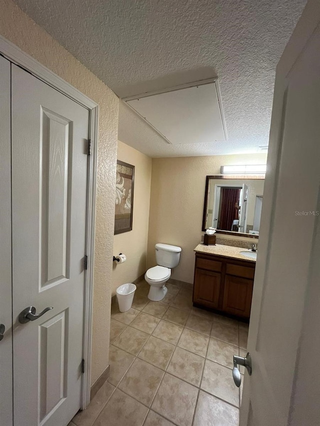 bathroom featuring a textured wall, toilet, vanity, a textured ceiling, and tile patterned floors