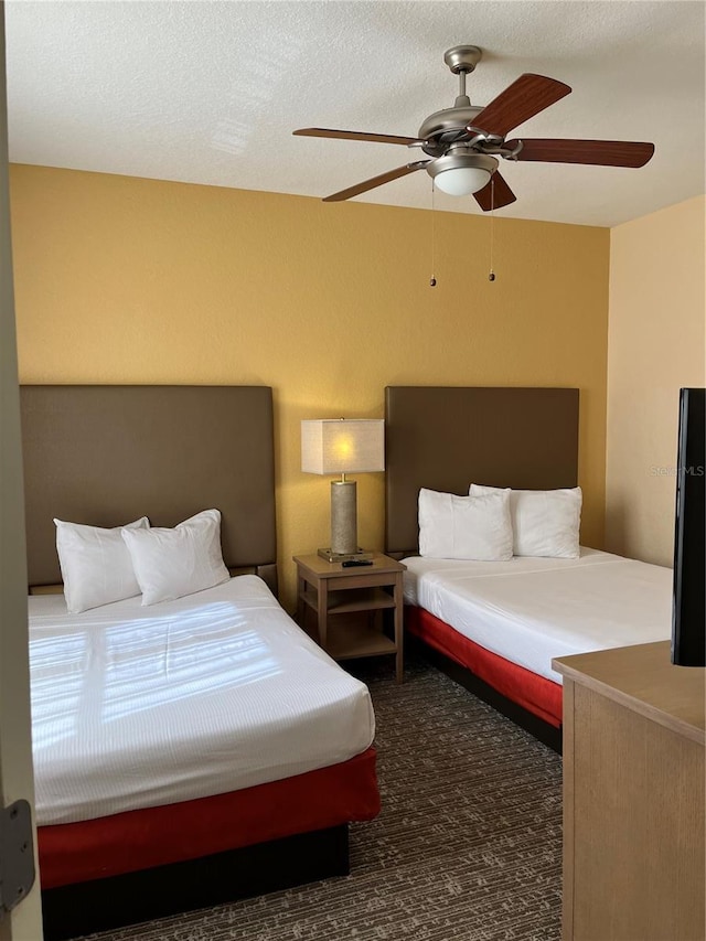 carpeted bedroom featuring ceiling fan and a textured ceiling