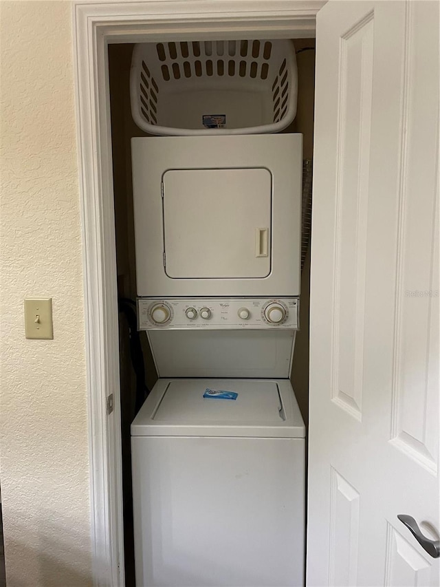 laundry area with stacked washing maching and dryer, laundry area, and a textured wall