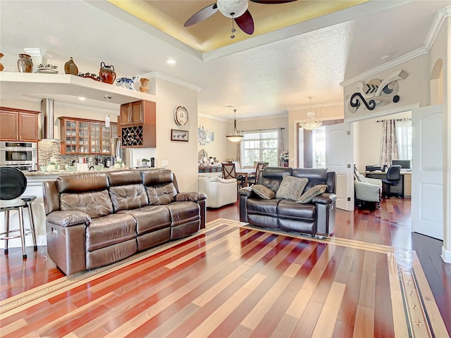 living room with hardwood / wood-style flooring, ornamental molding, a textured ceiling, and ceiling fan with notable chandelier