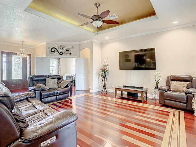 living room featuring ceiling fan, a raised ceiling, crown molding, wood-type flooring, and a textured ceiling