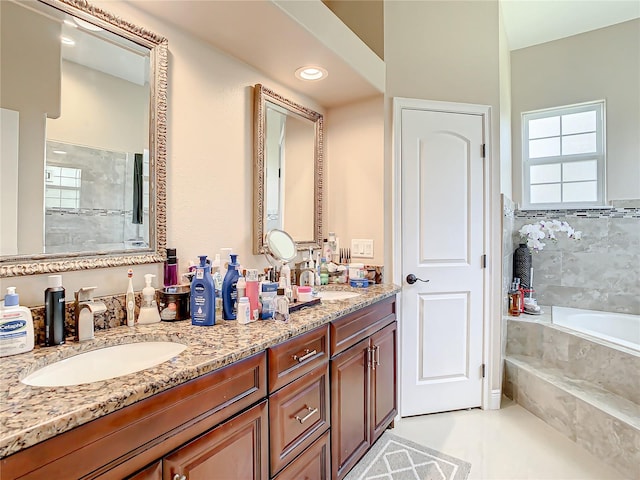 bathroom featuring a bathtub, tile flooring, dual sinks, and large vanity