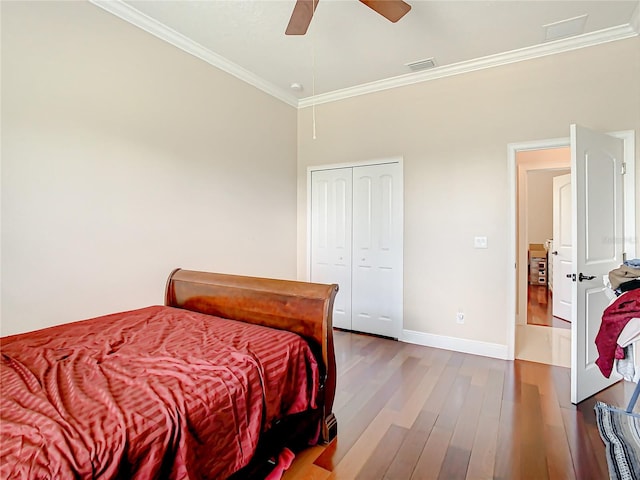 bedroom featuring ceiling fan, a closet, crown molding, and dark wood-type flooring