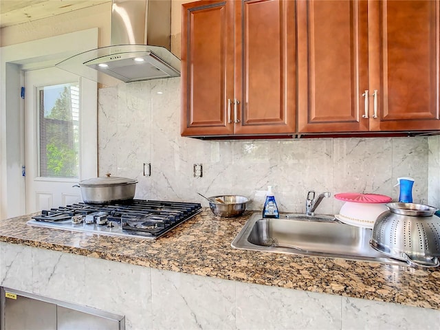 kitchen with backsplash, stone countertops, wall chimney exhaust hood, and stainless steel gas stovetop