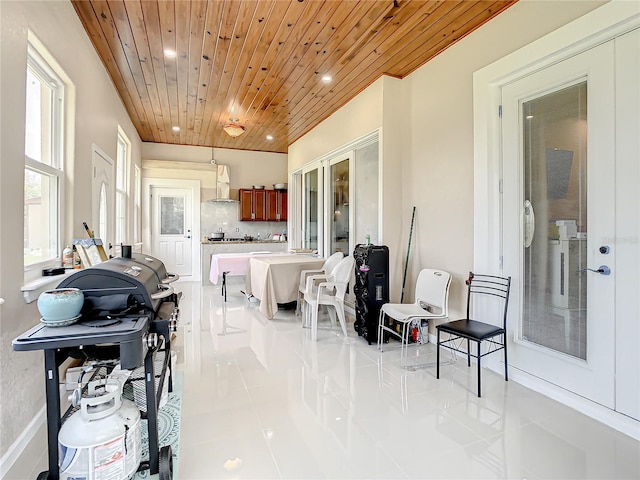 interior space featuring wall chimney range hood, tasteful backsplash, wood ceiling, and light tile floors