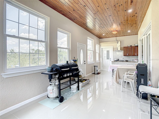 kitchen with wooden ceiling, backsplash, light tile floors, and wall chimney exhaust hood