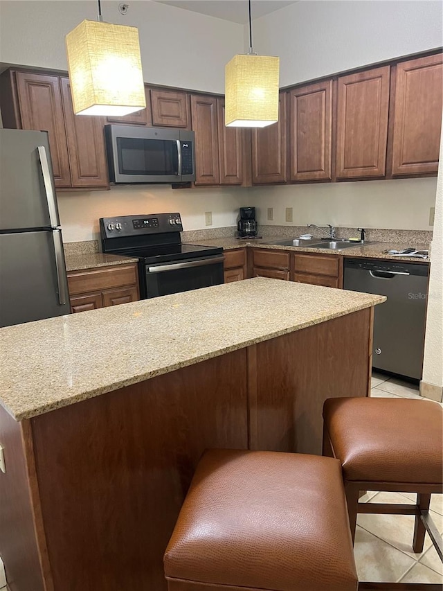 kitchen with pendant lighting, sink, light tile patterned floors, light stone countertops, and stainless steel appliances