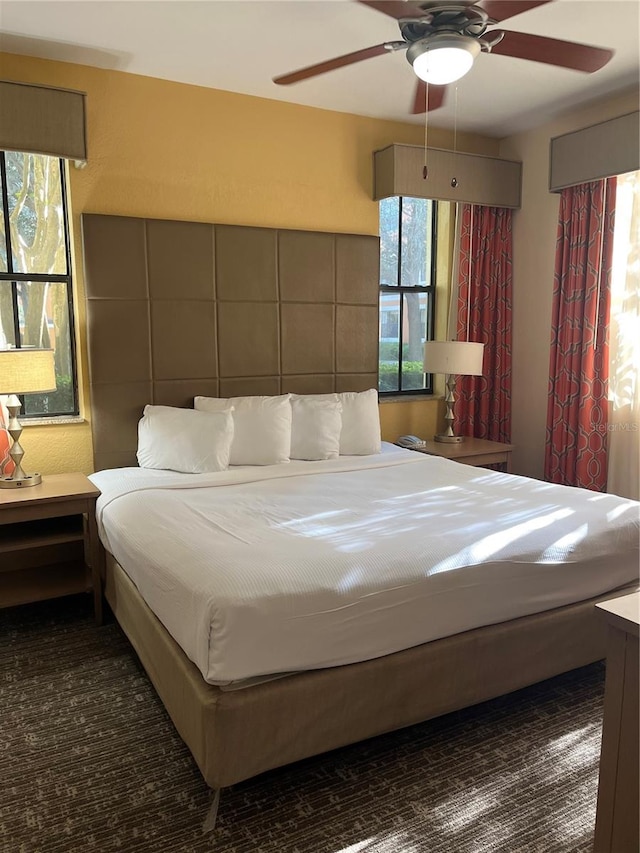 bedroom featuring ceiling fan, multiple windows, and tile walls