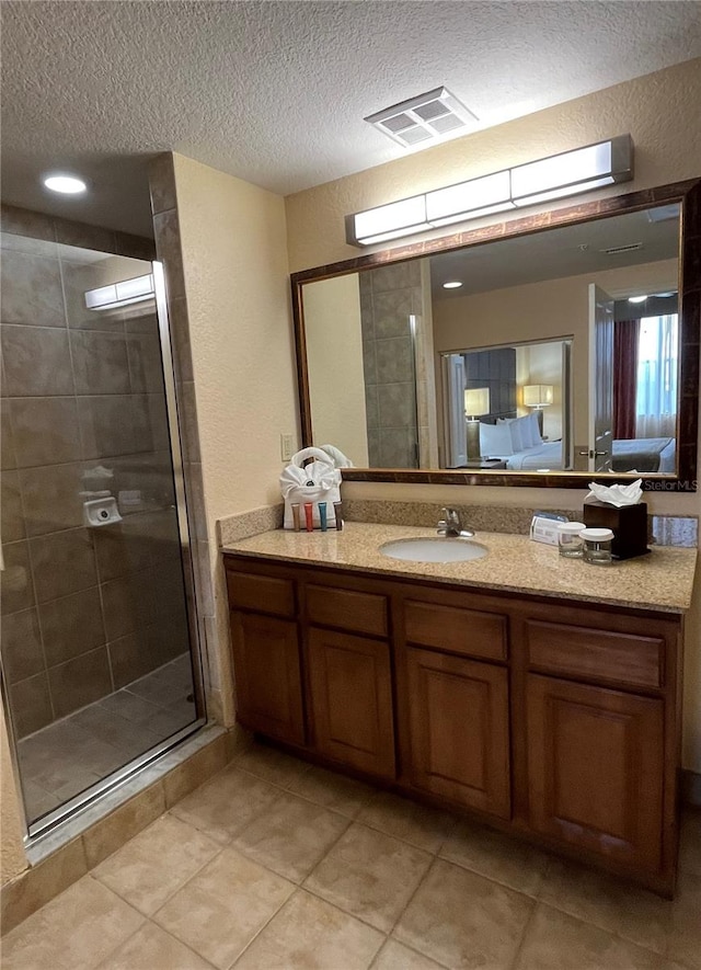 bathroom with a textured ceiling, tile patterned flooring, an enclosed shower, and vanity