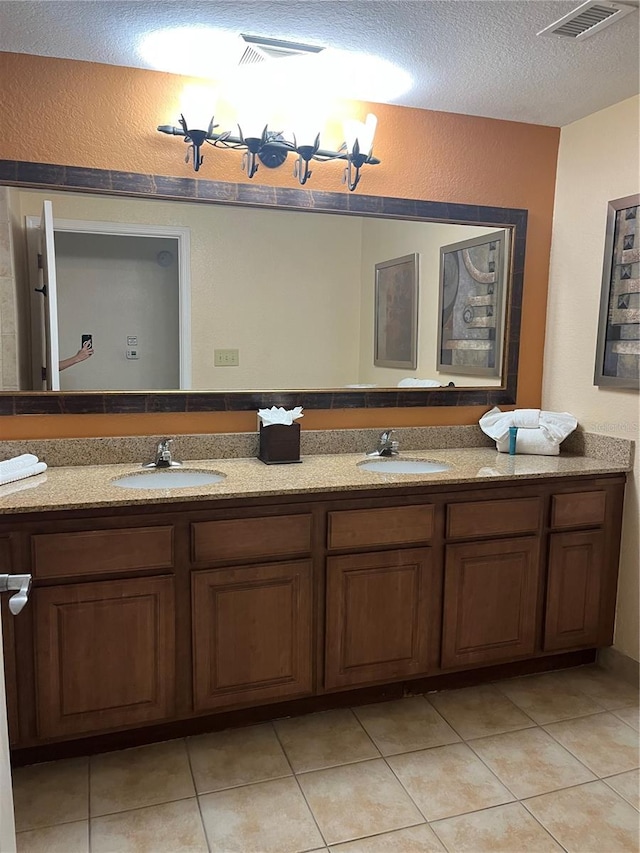 bathroom with a textured ceiling, tile patterned flooring, and vanity