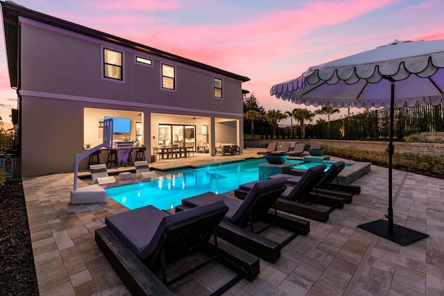 pool at dusk featuring a patio