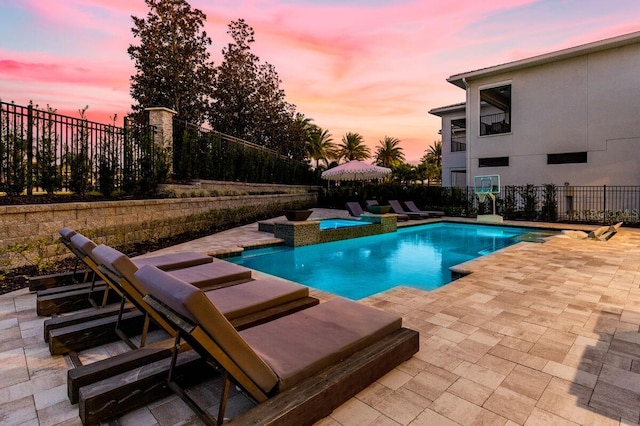 pool at dusk with a patio area