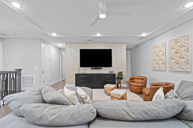 living room featuring a textured ceiling, ceiling fan, and light wood-type flooring