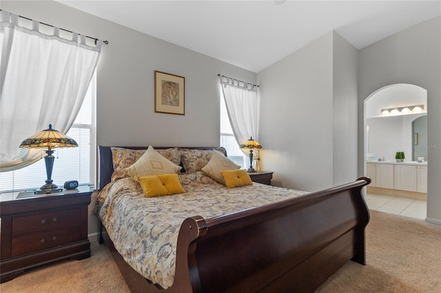 carpeted bedroom with connected bathroom, lofted ceiling, and multiple windows