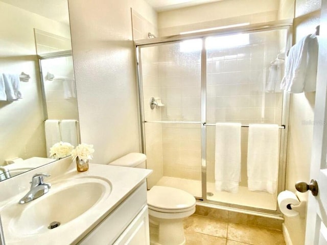 bathroom featuring an enclosed shower, toilet, vanity with extensive cabinet space, and tile flooring