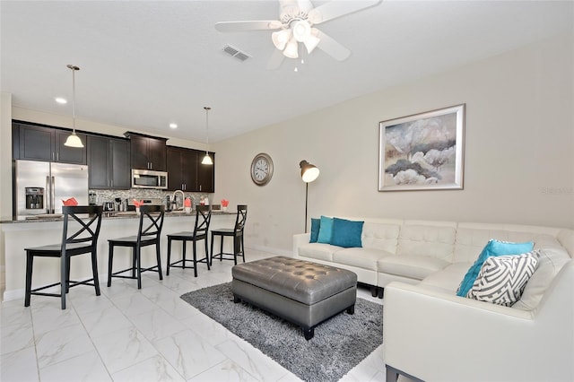 tiled living room featuring ceiling fan and sink