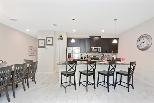 kitchen with light tile floors, appliances with stainless steel finishes, and a breakfast bar