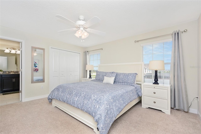 carpeted bedroom with a closet, sink, ceiling fan, and ensuite bathroom