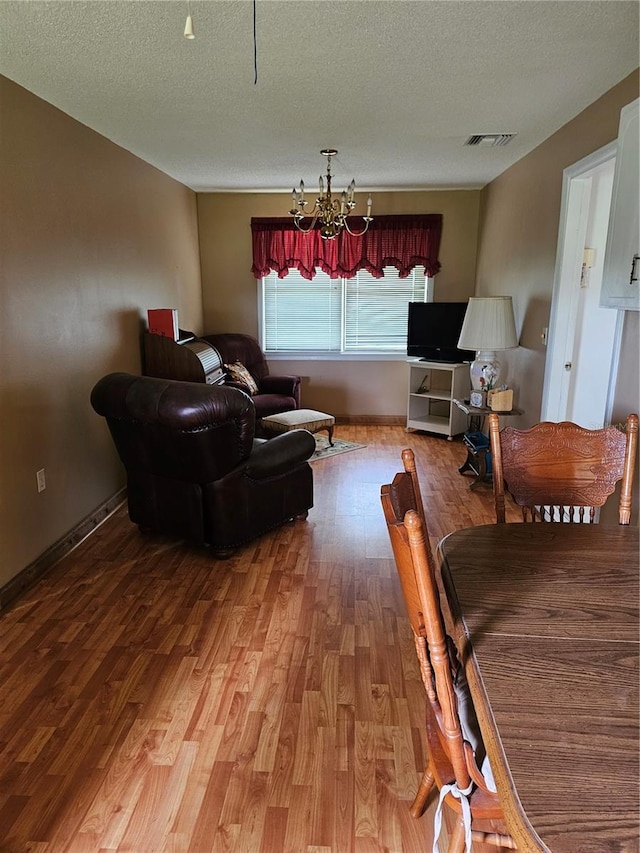 living room with a textured ceiling, a chandelier, and hardwood / wood-style flooring