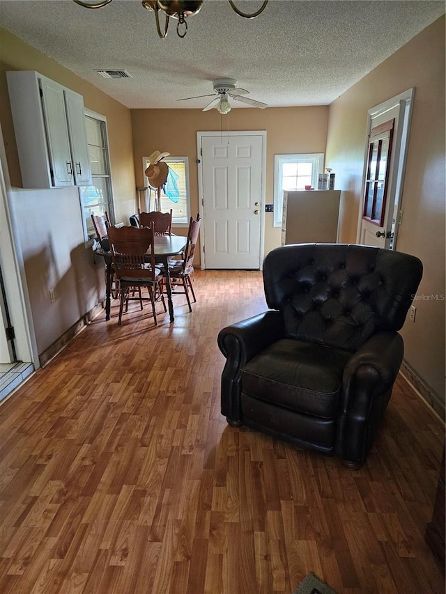 living room with a textured ceiling, wood-type flooring, and ceiling fan