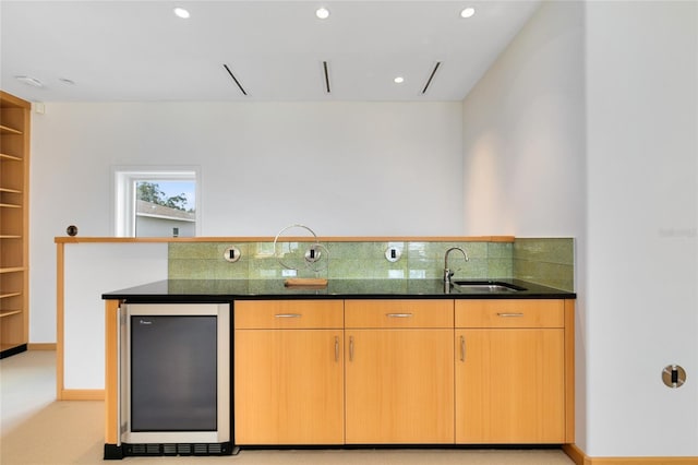 kitchen featuring stainless steel refrigerator, sink, and dark stone counters