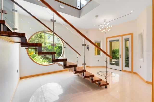 staircase with tile patterned floors, a wealth of natural light, a high ceiling, and a notable chandelier