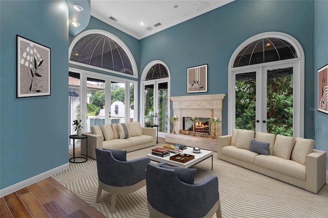 living room with a high ceiling, a healthy amount of sunlight, hardwood / wood-style floors, and french doors