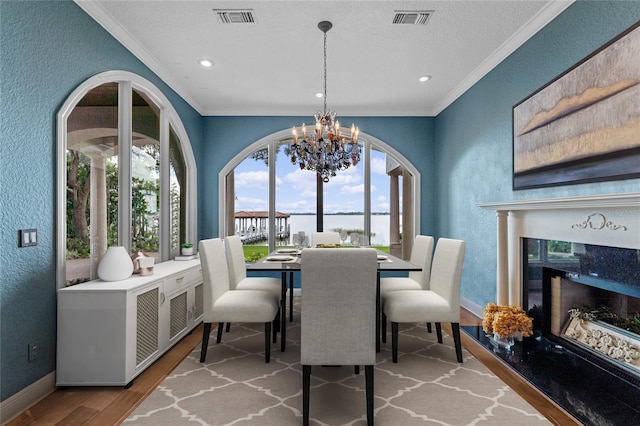 dining room featuring crown molding, a chandelier, a textured ceiling, hardwood / wood-style flooring, and a premium fireplace