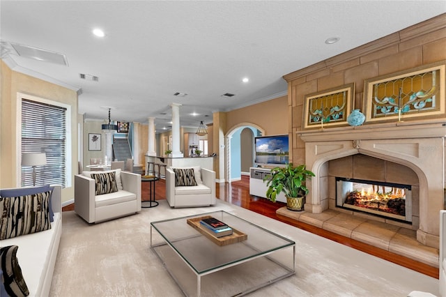 living room featuring ornamental molding, a tile fireplace, a textured ceiling, and light wood-type flooring