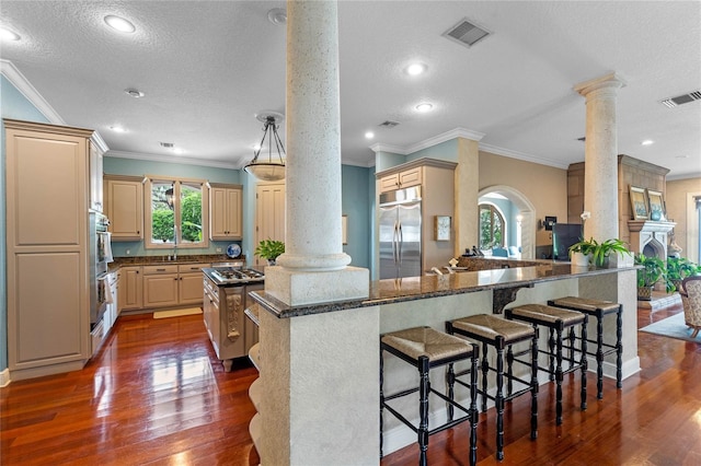 kitchen featuring a breakfast bar, appliances with stainless steel finishes, kitchen peninsula, and ornate columns