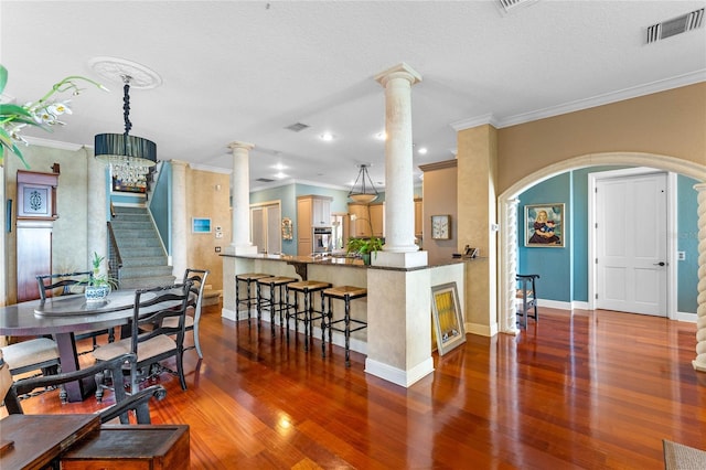 kitchen with decorative columns, oven, hardwood / wood-style flooring, kitchen peninsula, and crown molding