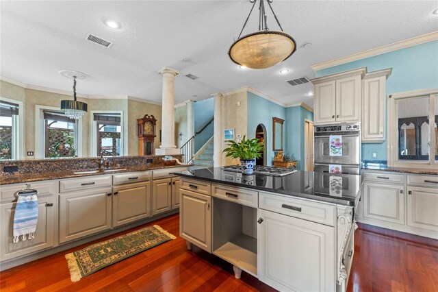 kitchen featuring dark wood-type flooring, sink, ornate columns, decorative light fixtures, and double oven