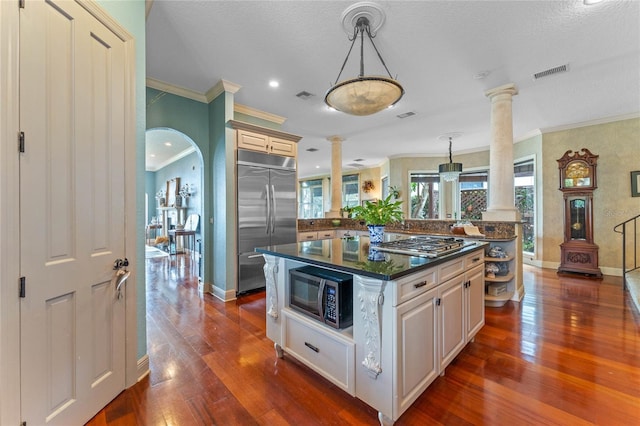 kitchen with pendant lighting, appliances with stainless steel finishes, a center island, and decorative columns