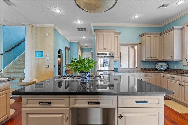 kitchen with stainless steel appliances, wood-type flooring, ornamental molding, and a textured ceiling