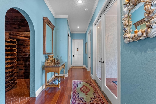 corridor featuring ornamental molding, dark wood-type flooring, and a textured ceiling