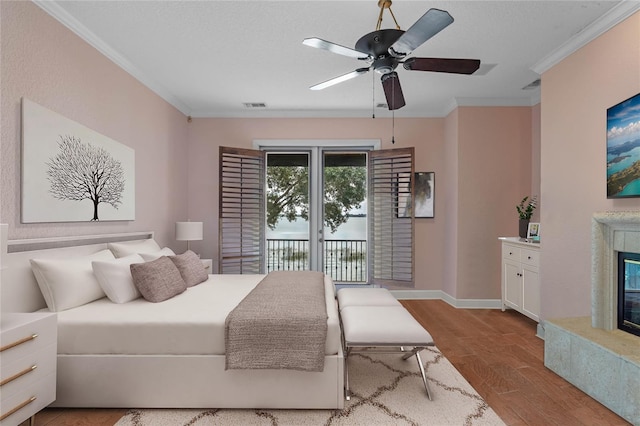 bedroom with crown molding, a textured ceiling, light wood-type flooring, ceiling fan, and a premium fireplace