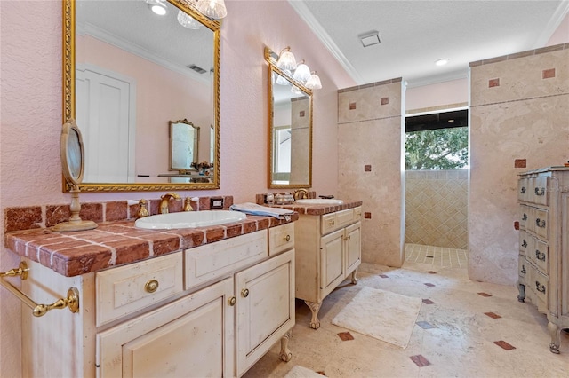 bathroom featuring crown molding, a tile shower, vanity, and a textured ceiling