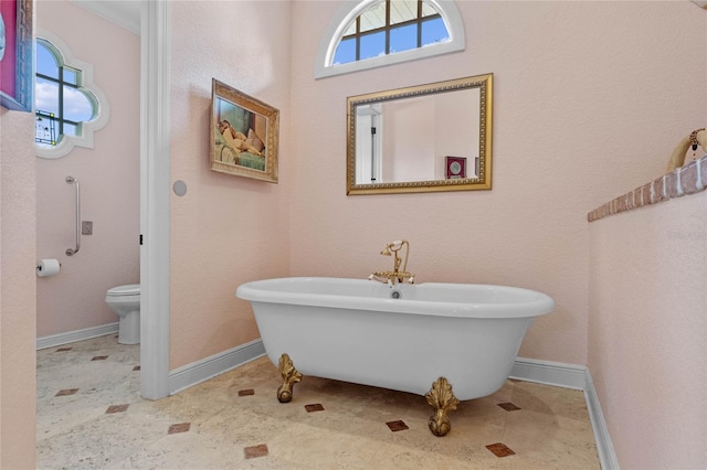 bathroom featuring tile patterned floors, toilet, and a tub